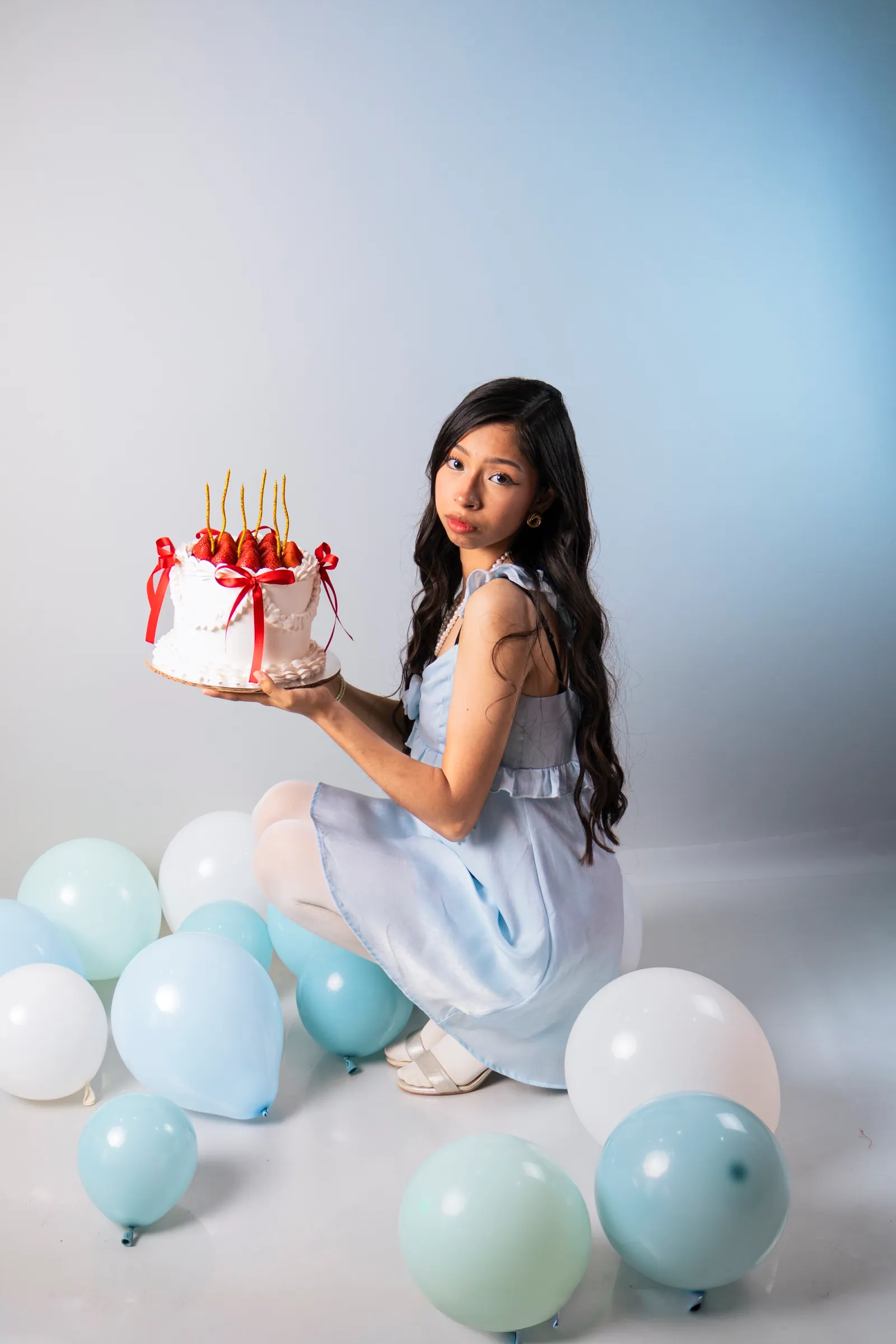 Libni sostiene un pastel con velas entre globos azules